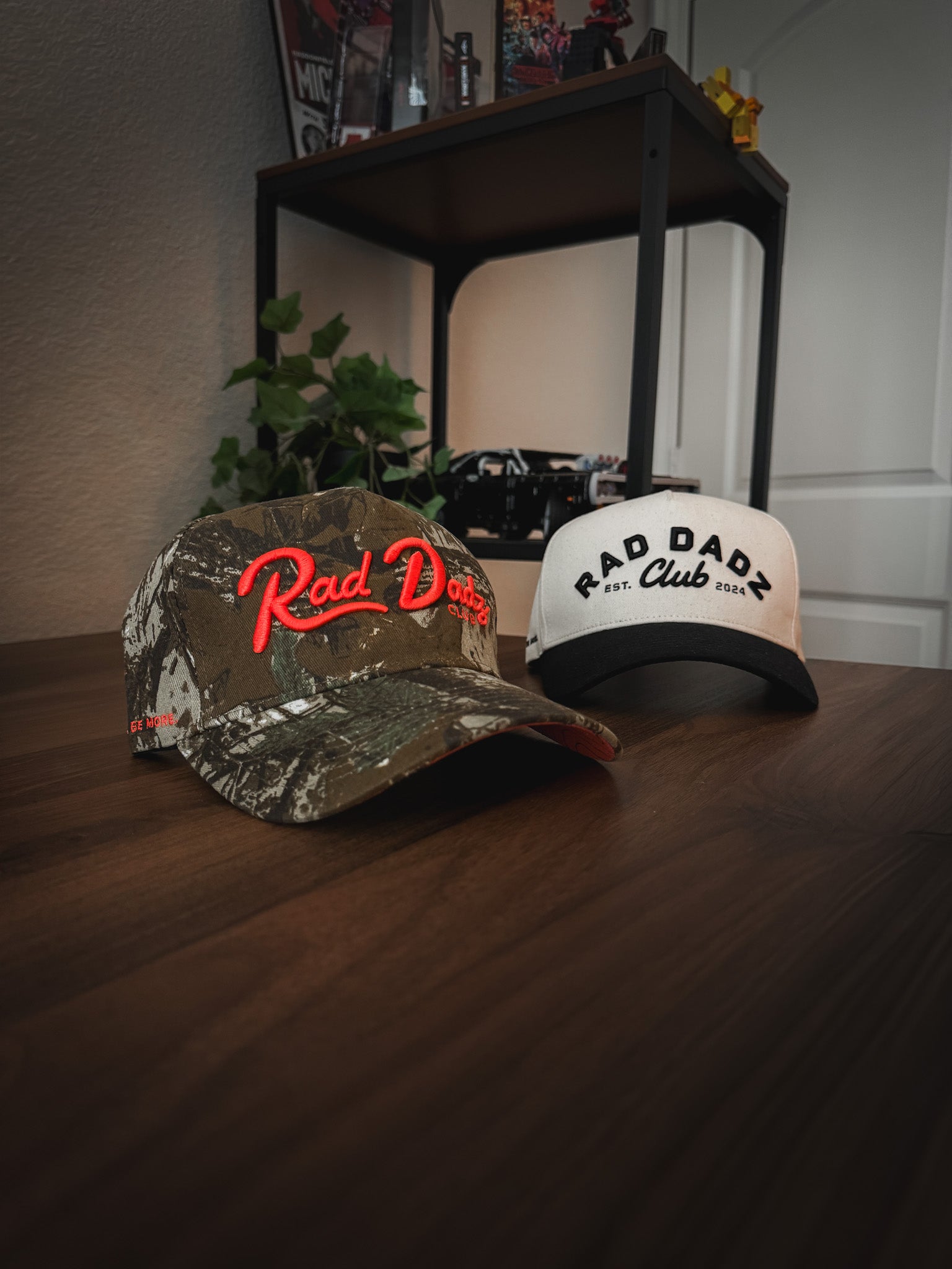 2 hats on a desk A camo hat and a tan hat on a desk